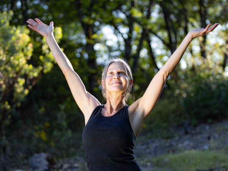A woman stretches her arms to the sky with a joyous expression