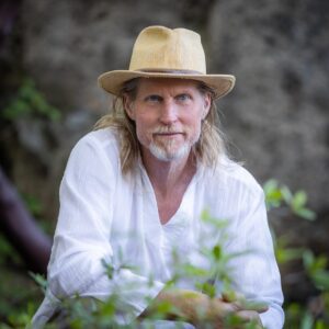 Image of Ragaia Belovarac wearing a white shirt and tan hat in a natural setting