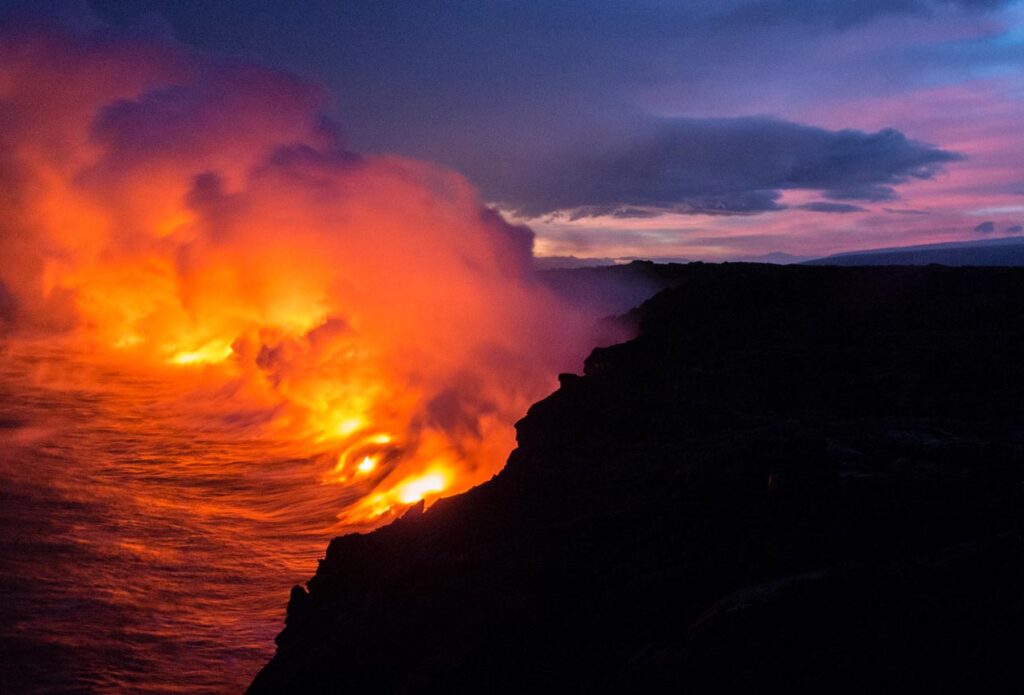 Lava enters the ocean creating orange steam. 